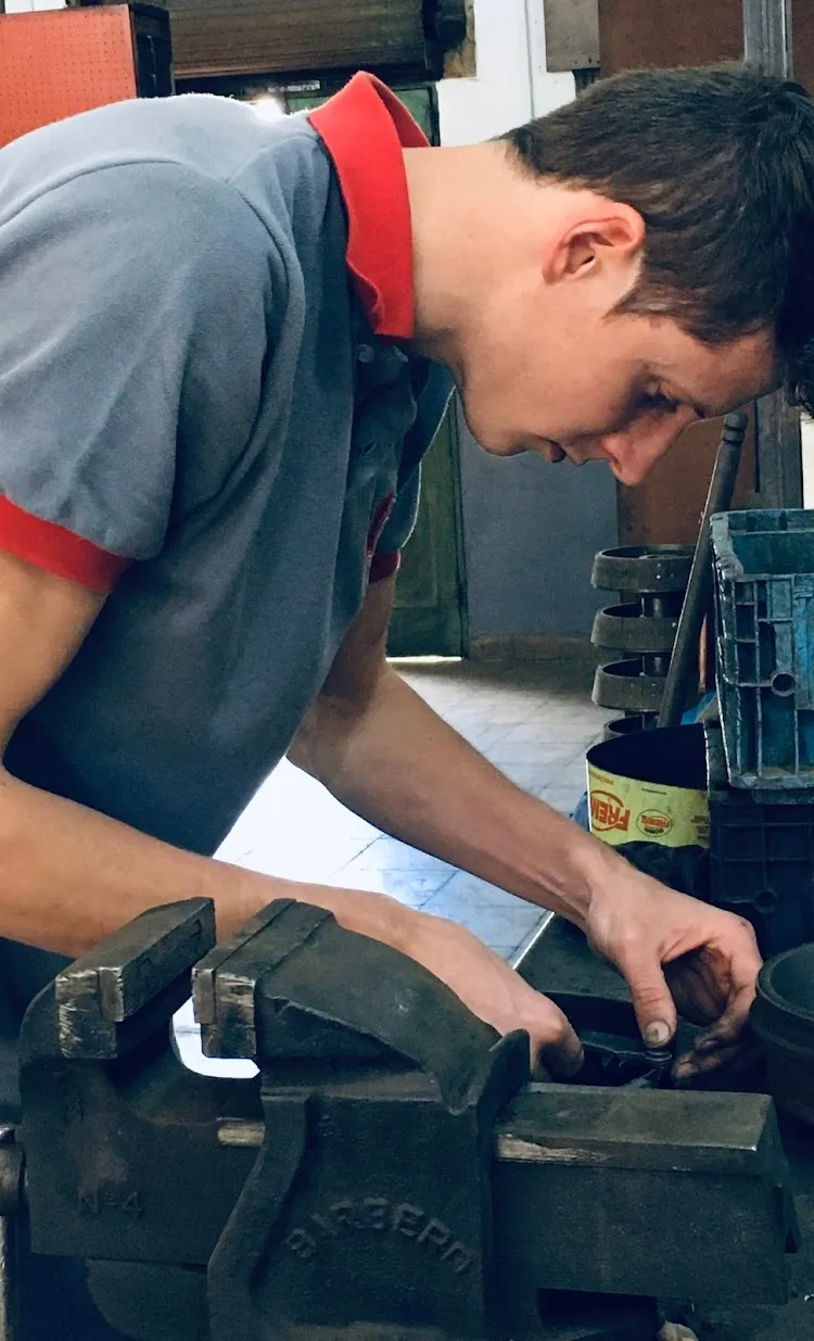 Mecánico rectificando pieza de freno en tornillo de banco